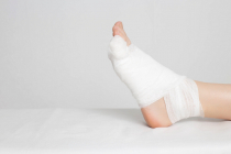 Man's bandaged foot with little finger on a white background. The concept of a fracture of the little finger on the leg with offset, copy space, deformation